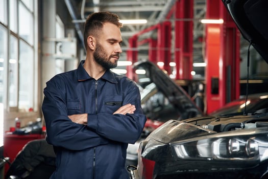 With, arms ,crossed, standing. Car repairman is in the garage with automobile photo