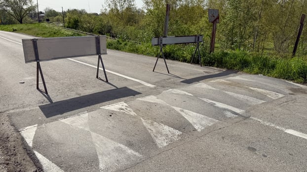 Empty rural road with traffic barriers under sunny sky, emphasizing travel safety and rural infrastructure, Earth Day concepts photo