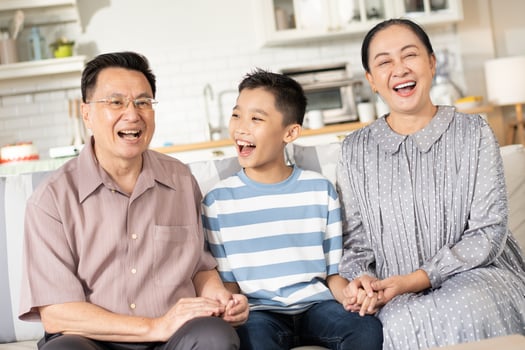 Happy Asian grandson and grandparents relax sitting on couch in the living room looking at camera. Family generation love bonding, people smiling and laughing together at home photo