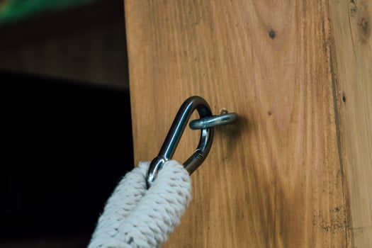 Metal clip connects rope to sturdy wooden beam during outdoor activity or construction photo