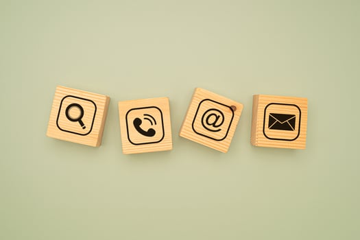 Top view of wooden cubes with symbols of a magnifying glass, mobile, address, and email on a green background photo