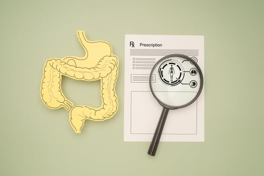 Top view of an intestine symbol made from yellow paper and a magnifying glass over the medical prescription on a green background photo