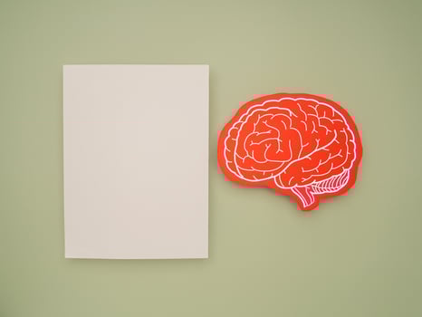 A blank white paper and a red brain shape symbol on a green background photo