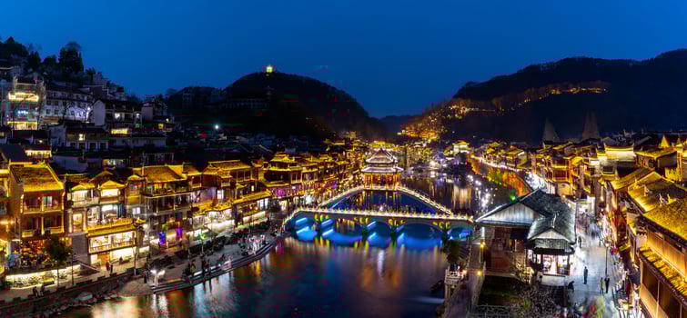 Feng Huang Ancient Town and tourist boats on Tuo Jiang River photo