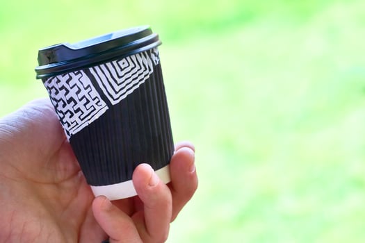 Relax coffee break. Men hand with a cup of coffee on green photo