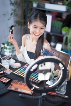 a woman is holding a phone and looking at her makeup photo