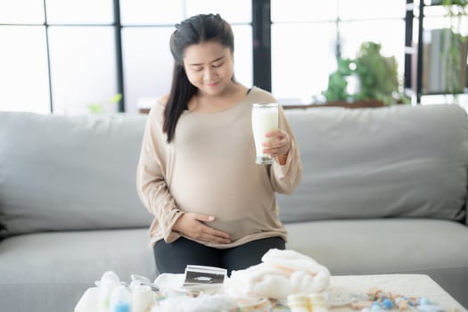 Pregnant asian woman drinking milk at home relaxation and Self-care Pregnancy drinking a glass of fresh milk mother Positive life moment photo
