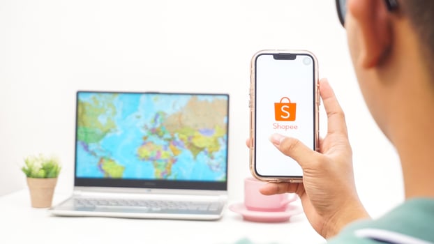 Yogyakarta, Indonesia, 2025 - Man holding smartphone showing Shopee, electronic commerce or online shopping platform application on the screen isolated on white background photo