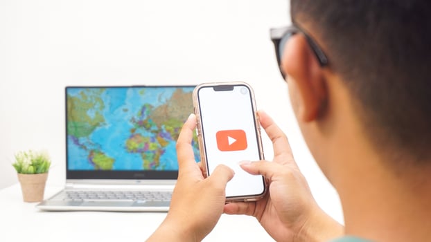Yogyakarta, Indonesia, 2025 - Man holds smartphone with Youtube platform application on the screen isolated on white background photo