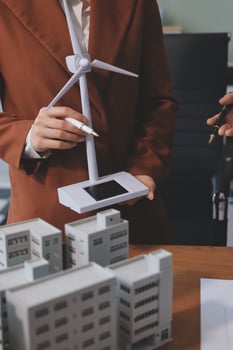 A woman in a suit holding a tablet computer and a wind turbine photo