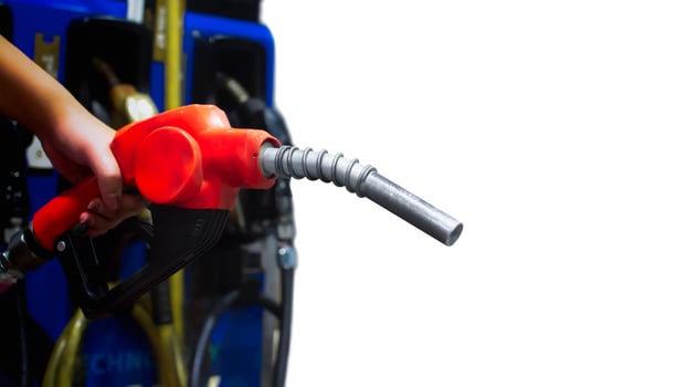 A hand holds a red gasoline pump nozzle at a gas station, ready to refuel a vehicle. gas prices, petrol station. photo