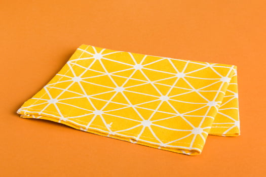 top view with yellow empty kitchen napkin isolated on table background. Folded cloth for mockup with copy space, photo