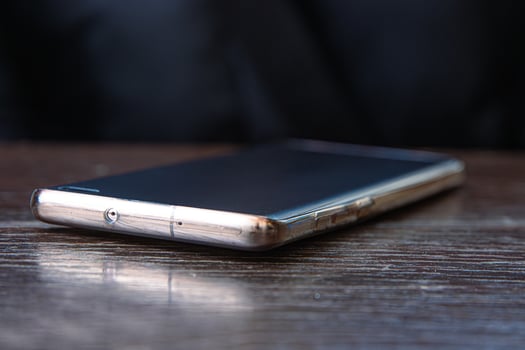 Closeup of the black screen smartphone on a dark brown wooden cafe table surface. Selective focus 04 photo