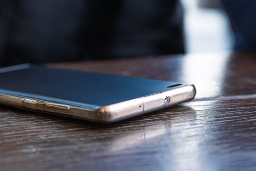 Closeup of the black screen smartphone on a dark brown wooden cafe table surface. Selective focus 03 photo