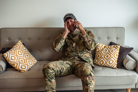 Depressed soldier crying while making a phone call at home, suffering from post-traumatic stress disorder photo