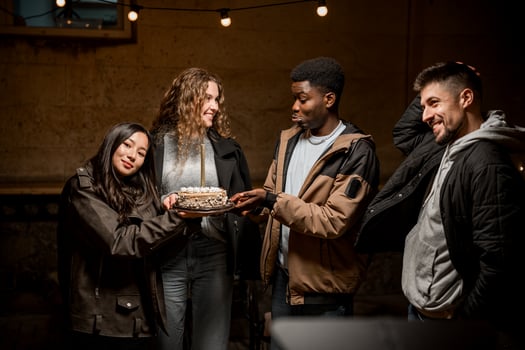 Friends celebrating with a cake in a cozy indoor setting during a night gathering photo