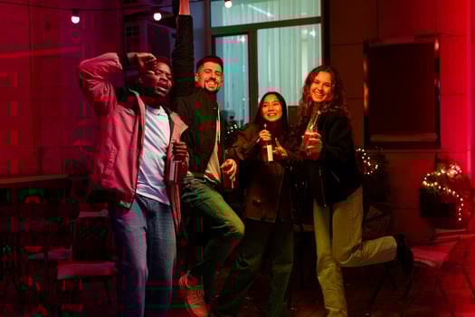Group of friends celebrating joyfully at party with drinks in festive outdoor setting at night photo