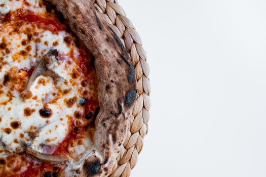 Close up of wood fired pizza with cheese and tomato on woven mat photo
