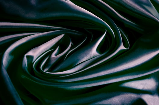 Top view of polished dark grey silk cloth with silky sheen and beautiful natural draping. Suitable for design and wallpaper background photo