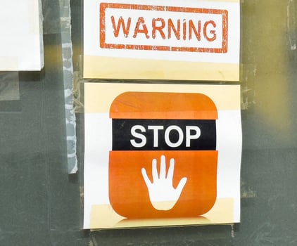 Warning and stop sign with hand icon on glass surface for safety awareness photo