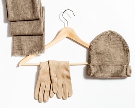 Knitted hat, scarf and suede gloves on clothes hanger. Fashion warm clothing concept photo