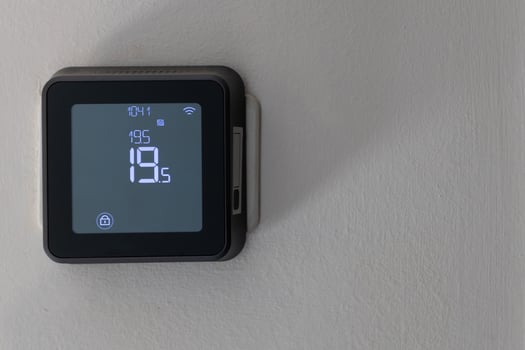 Smart digital thermostat on white wall photo