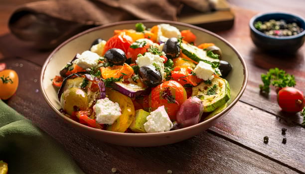A Mediterranean-style summer meal featuring a large bowl of roasted vegetables, olives, and feta cheese. photo