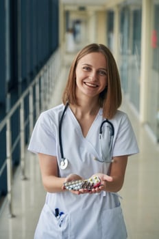 Bunch of pills ,in hands. Female doctor in white coat is in the hall photo