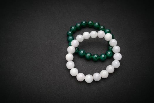 Top view of white and green jade rings on a black background. Space for text. photo