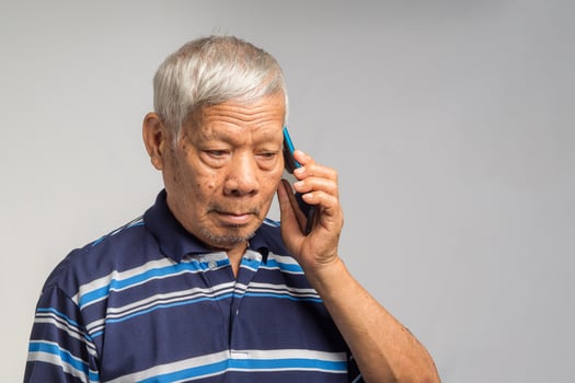 Portrait of a senior man using a smartphone while standing on a gray background photo
