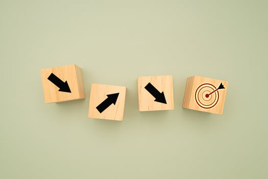 Wooden cubes with black arrows pointing to the dartboard icon on a green background photo