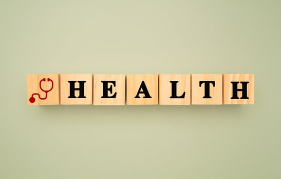 Top view of wooden cubes with words HEALTH and a stethoscope icon on a green background photo