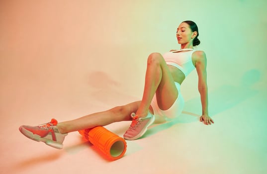 Using roller., Young, fitness, woman in sportive clothes against background in studio photo