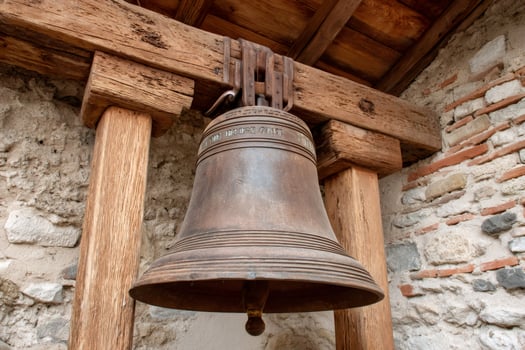 Large bell hanging from wooden beams in historic building photo