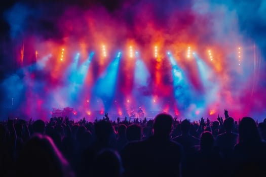 Crowd cheering and raising hands at music concert with colorful stage lights and smoke photo