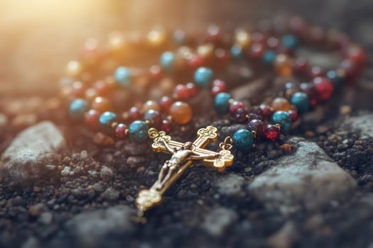 Rosary beads and crucifix resting on rocky ground photo