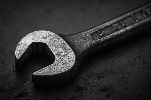 Close up of a rustic metal wrench on dark surface photo
