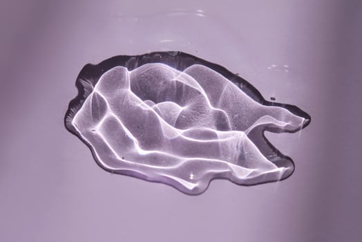 A drop of oil serum on a purple background with beautiful highlights. photo