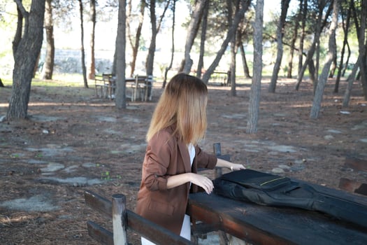 Girl Walks With Guitar Instrument Case Behind Her In The Park photo