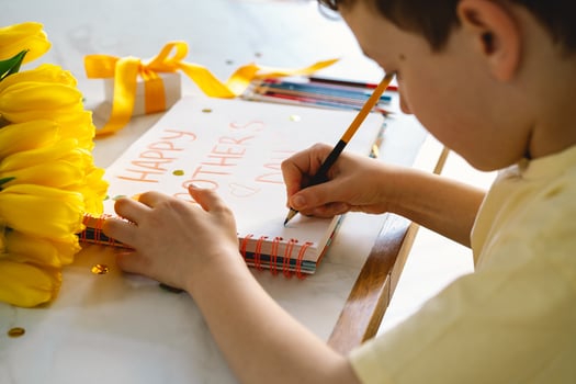 A boy diligently creating a Mother's Day card photo