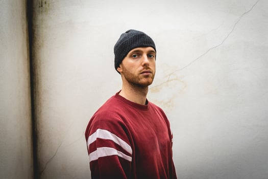 portrait of young rapper posing in front of a white wall photo