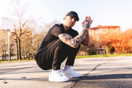 a young tattooed rapper slumped in the middle of an outdoor basketball court in the suburbs photo