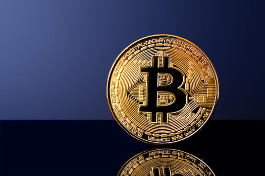 Shiny bitcoin coin on reflective surface with dark blue background photo