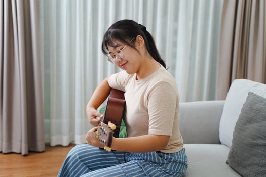 Woman play acoustic guitar and singing on the sofa in living room at home photo