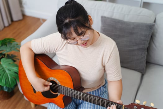 Happy Asia women play acoustic guitar and singing on the sofa in living room at home photo