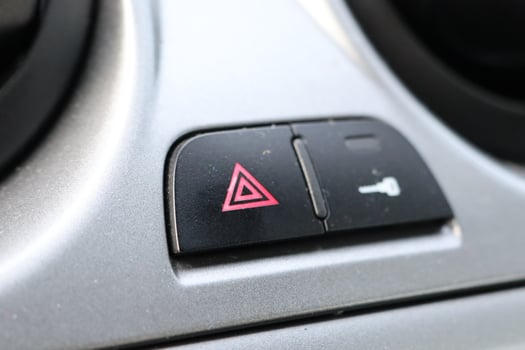This specific button is designed to activate the emergency alert signal on a cars dashboard photo