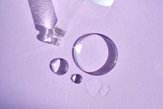 A drop of serum with a pipette on a purple background. photo