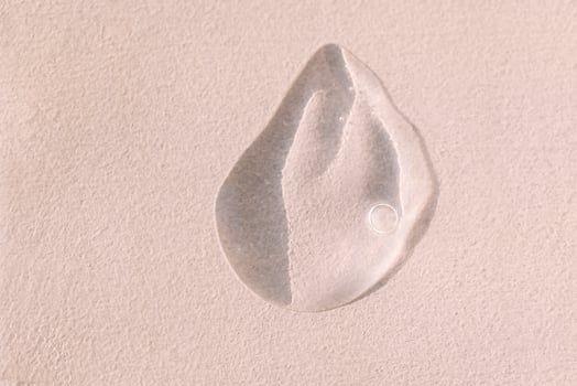 Close-up of a transparent gel smear with bubbles. Cosmetic products. A drop of serum or essence on a textured background. Bright sunlight. photo