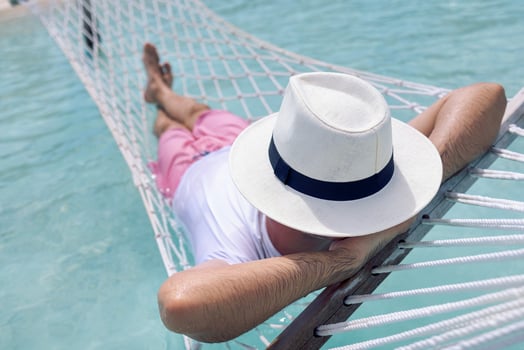 A young man in summer clothes and a hat is lying in a hammock in clear sea water photo