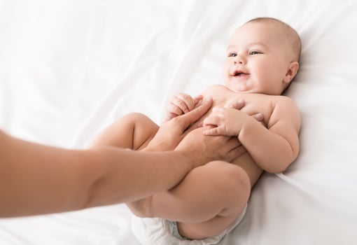 Baby healthcare. Woman physician massaging cute infant, professional newborn gymnastics, top view photo
